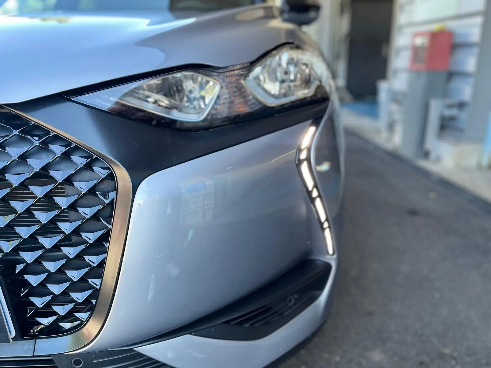 Gros plan sur l'avant droit gris métallisé du DS3 Crossback Performance Line, mettant en valeur la calandre et les feux LED.