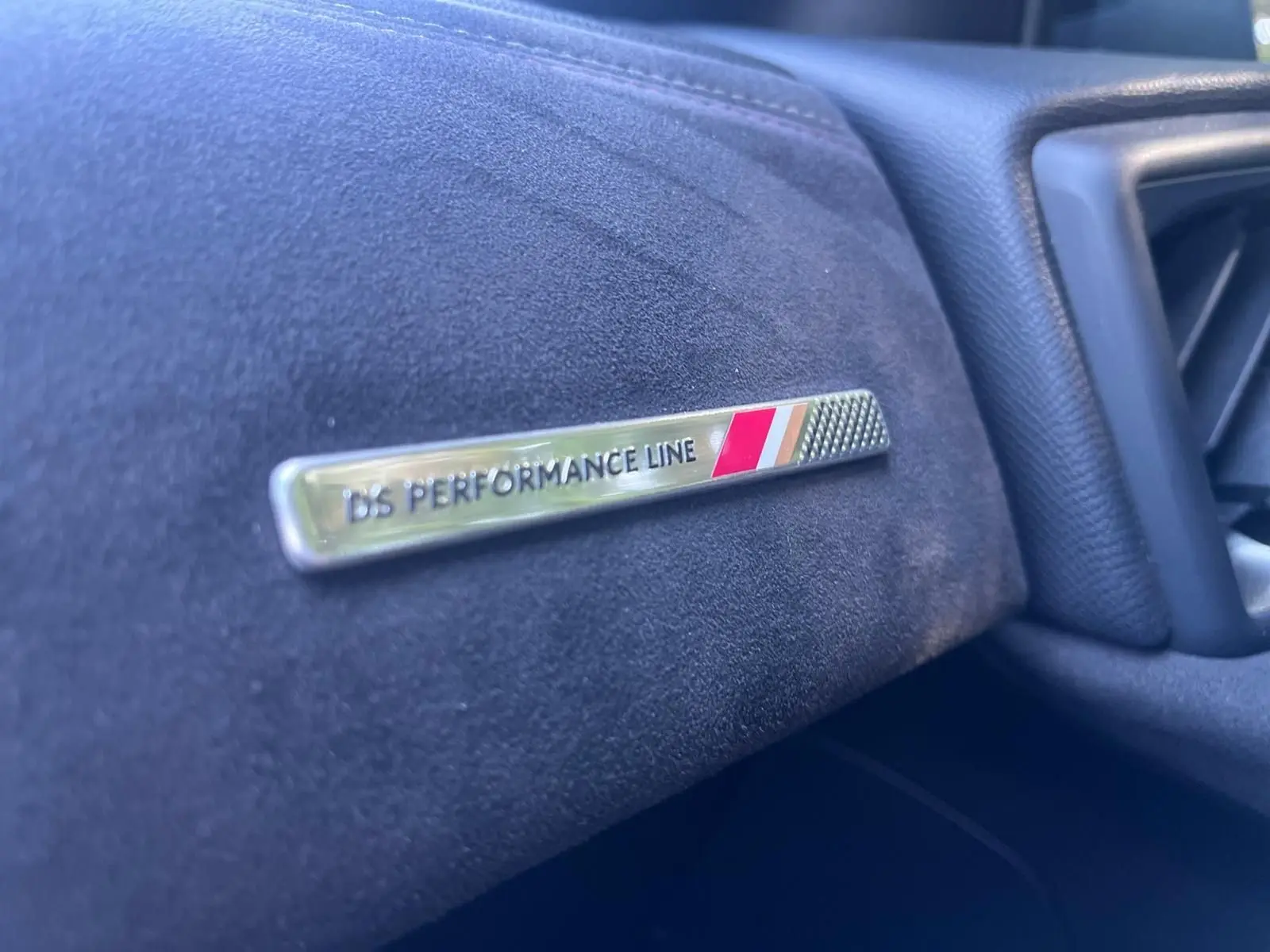 Gros plan sur le badge DS PERFORMANCE Line sur la planche de bord en tissu noir du DS3 Crossback 2022.