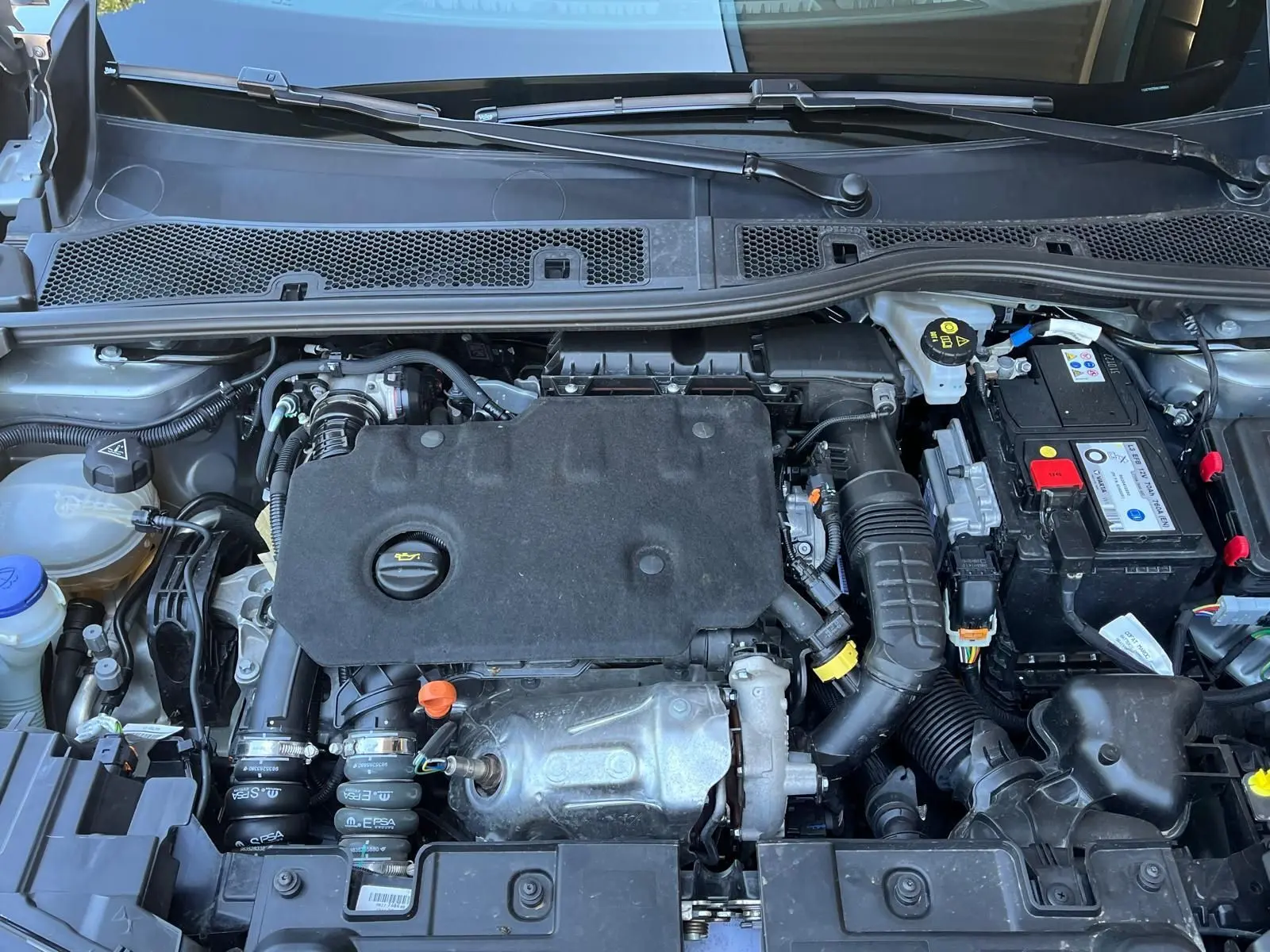 Vue plongeante sur le moteur diesel du DS3 Crossback Performance Line 2022, avec batterie et composants visibles.