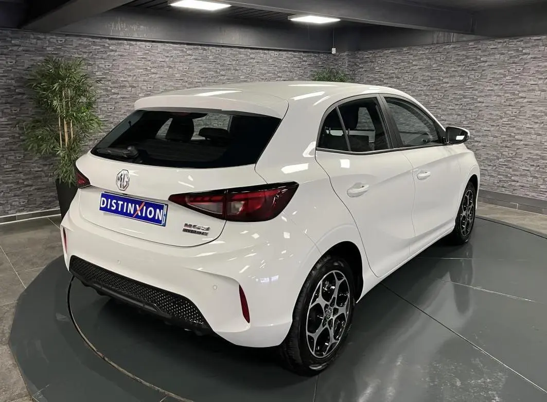 Vue 3/4 arrière droite d'une MG3 blanche 2024 avec jantes alliage et feux arrière LED dans un showroom.