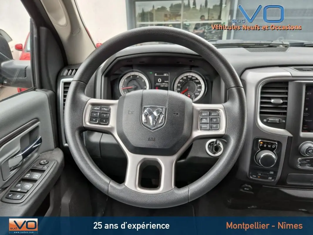 Vue intérieure centrée sur le volant du Dodge RAM Crew SLT Classic Black Package gris foncé, tableau de bord et commandes visibles.