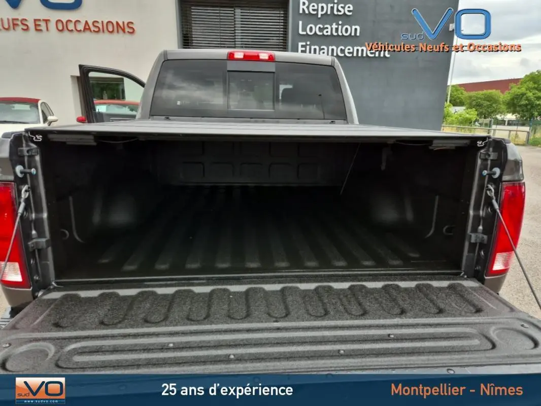 Vue arrière du Dodge RAM Crew SLT Classic Black Package gris foncé 2022 avec la benne ouverte, montrant l'espace de chargement vide.