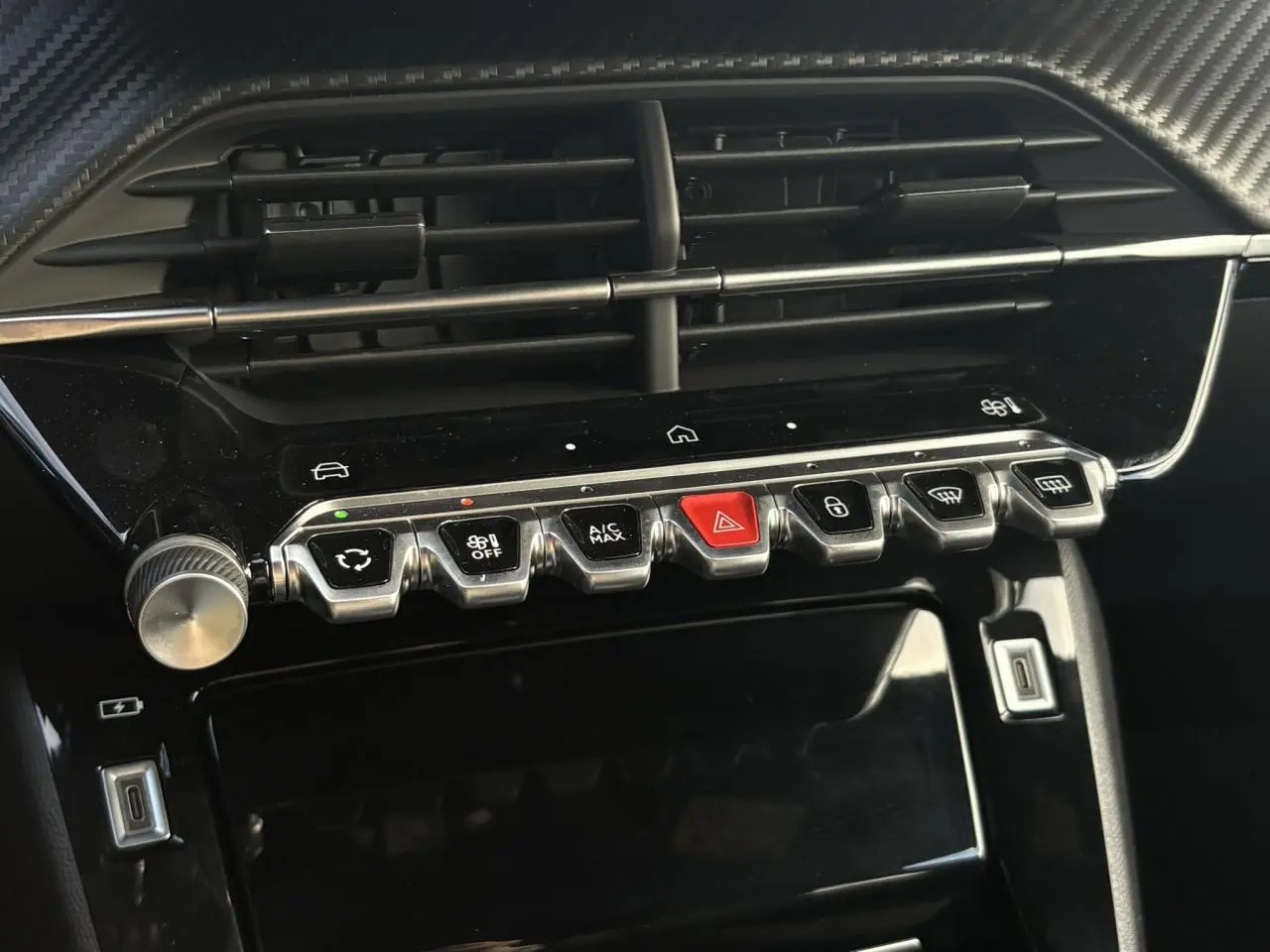 Gros plan sur la console centrale noire brillante du Peugeot 2008 Hybrid 145 e-DSC6 Allure avec boutons métallisés et écran tactile éteint.