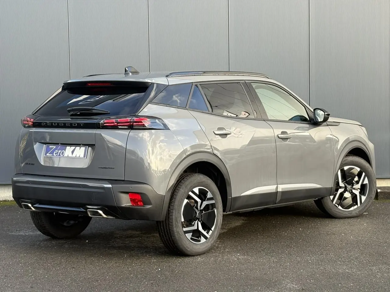 Peugeot 2008 Hybrid 145 gris Selenium en 3/4 arrière droit, jantes bi-ton et feux arrière LED 3 griffes visibles.