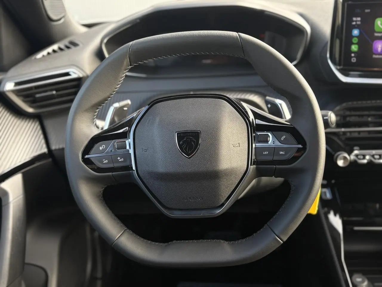 Vue rapprochée du volant compact en cuir noir avec commandes multimédia du Peugeot 2008 Hybrid 145 e-DSC6 Allure.