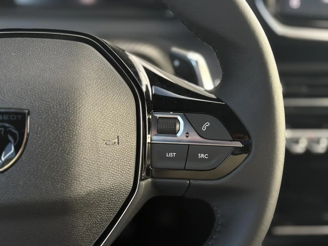 Gros plan sur les commandes multimédia à droite du volant cuir noir du Peugeot 2008 Hybrid 145 e-DSC6 Allure.