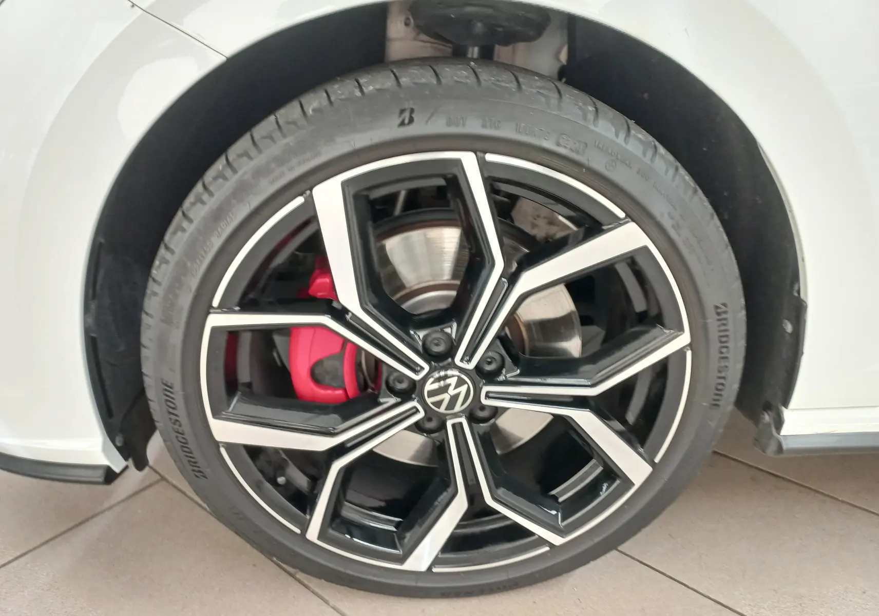 Gros plan sur la roue avant gauche d'une Volkswagen Polo GTI 2024 blanc pur avec étrier de frein rouge.