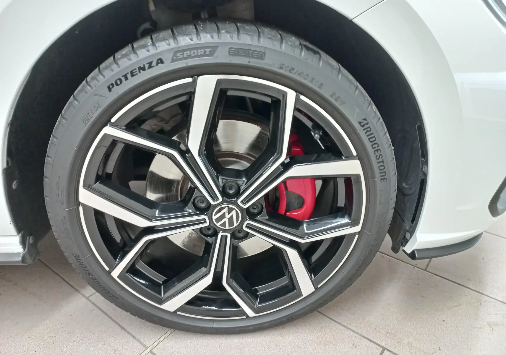 Gros plan sur la roue avant droite d’une Volkswagen Polo GTI 2024 blanche, jante noire et argent avec étrier de frein rouge.