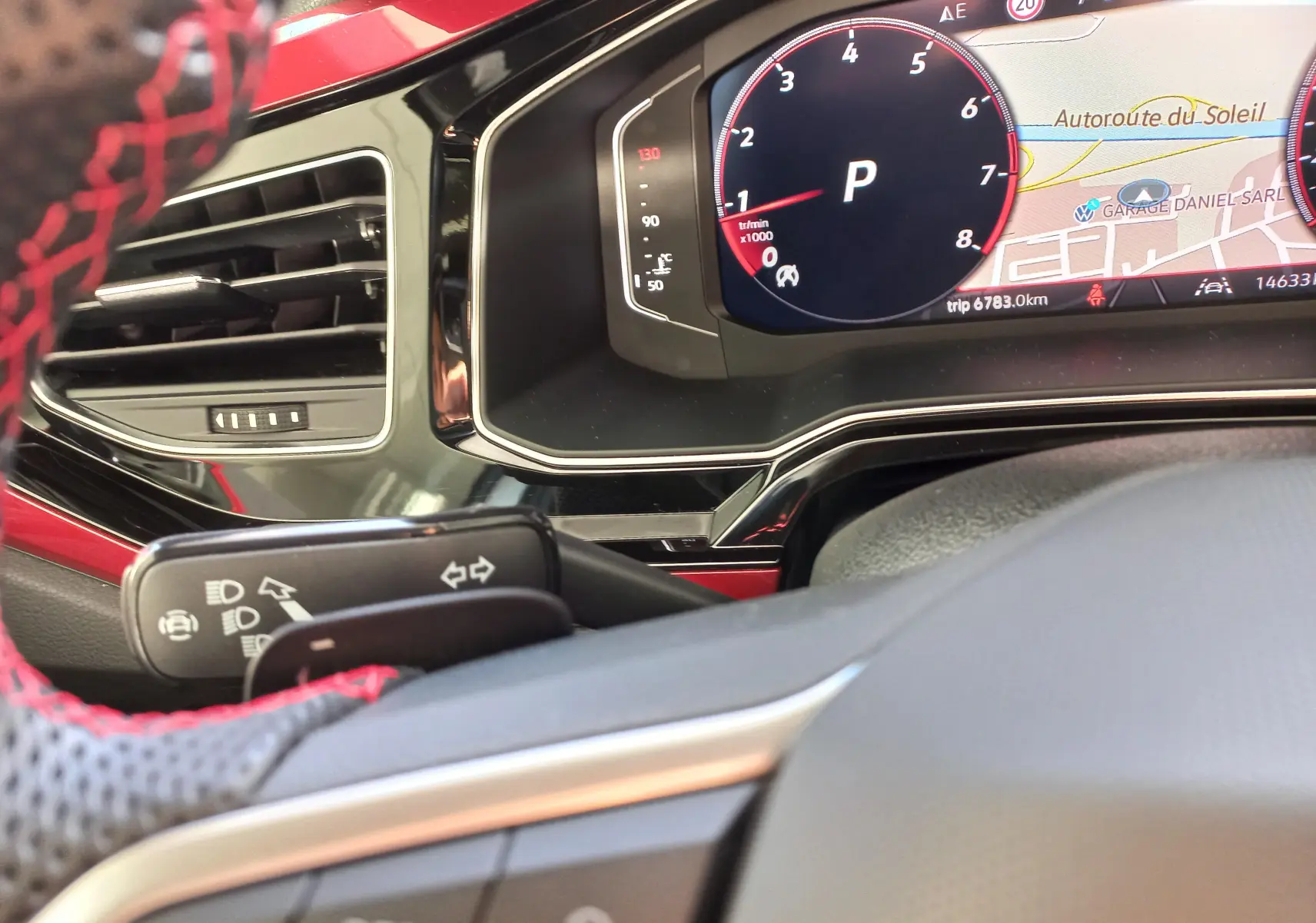 Tableau de bord et volant partiel d'une Volkswagen Polo 2024, avec affichage numérique et volant au cuir noir et rouge.