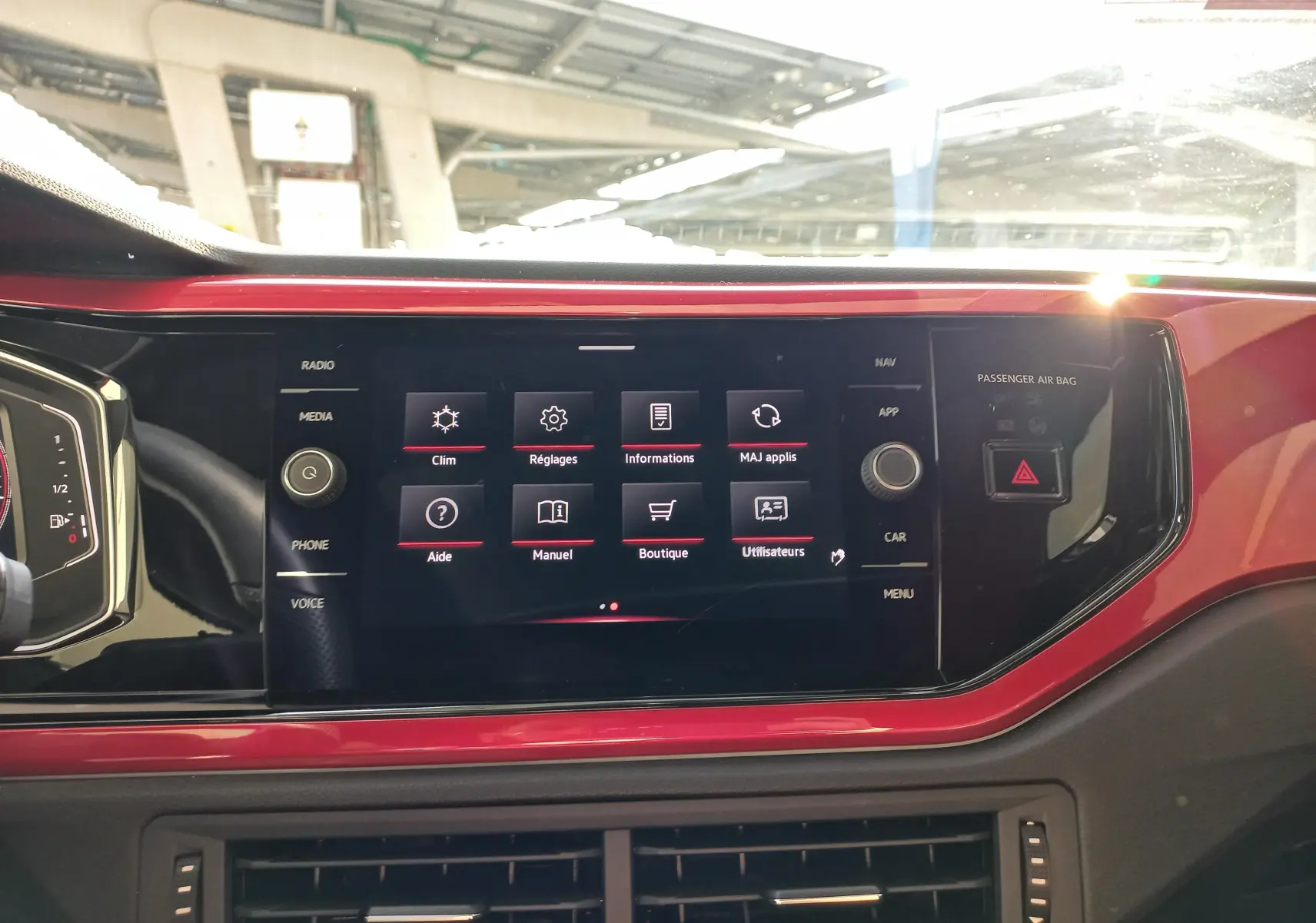 Vue intérieure du tableau de bord de la Volkswagen Polo 2024 avec écran tactile central et finition rouge brillante autour.