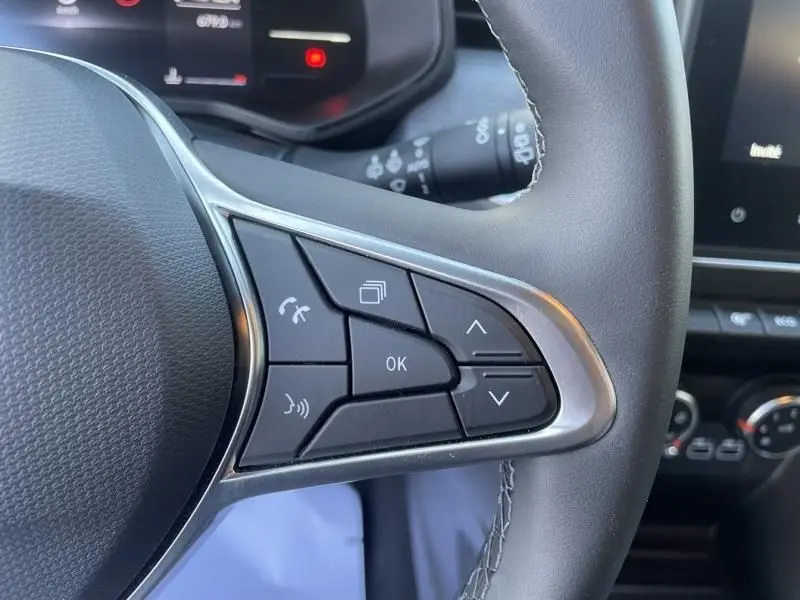 Gros plan sur les commandes multifonctions à droite du volant de la Renault Clio V gris métal, avec boutons de navigation et appel.