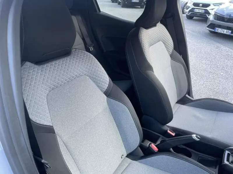 Vue intérieure des sièges avant en tissu gris clair et noir de la Renault Clio V DCI 100 Evolution 2025, côté conducteur ouvert.