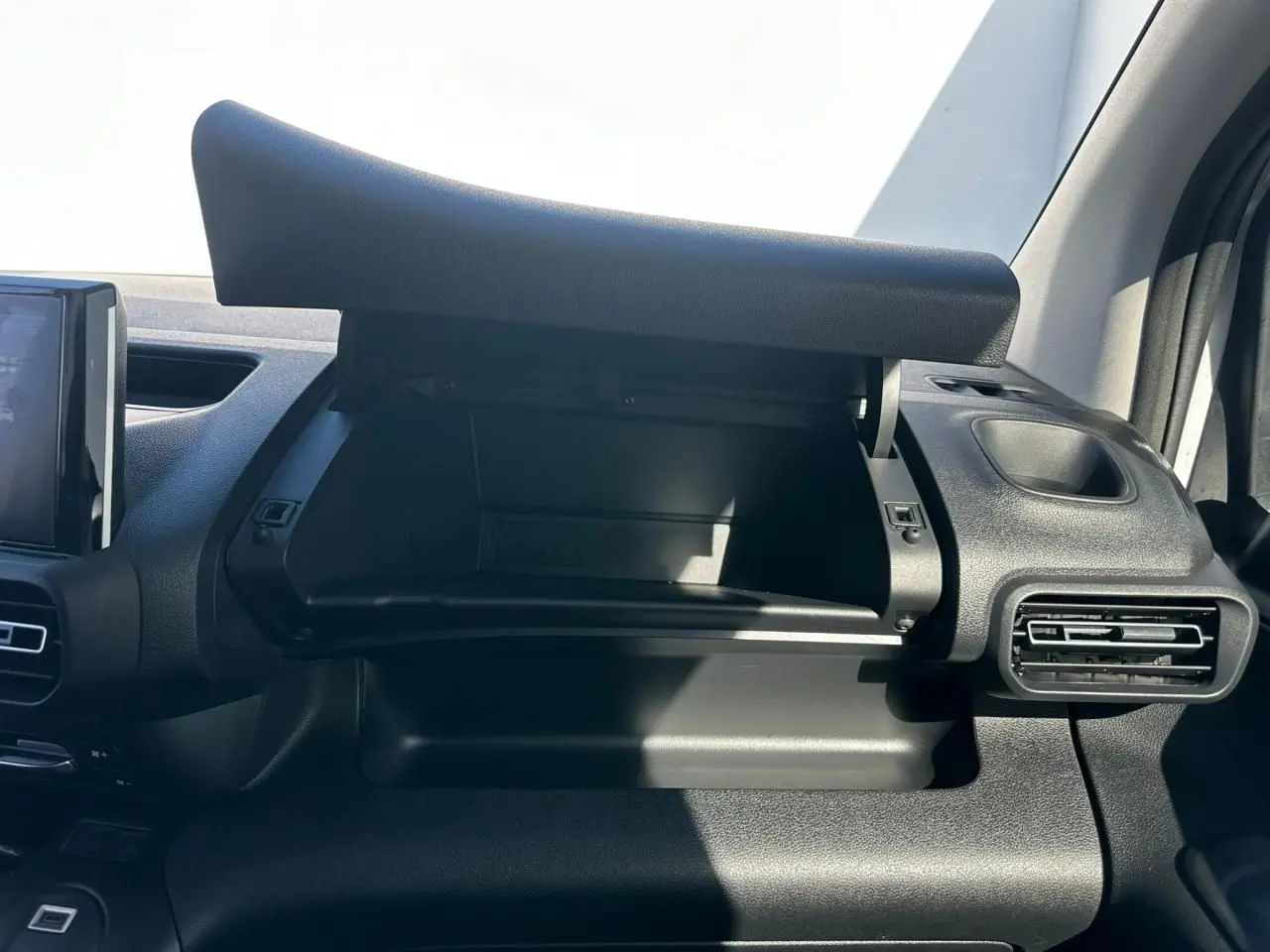 Vue intérieure côté passager du Citroën Berlingo blanc Icy, avec boîte à gants ouverte et tableau de bord noir.