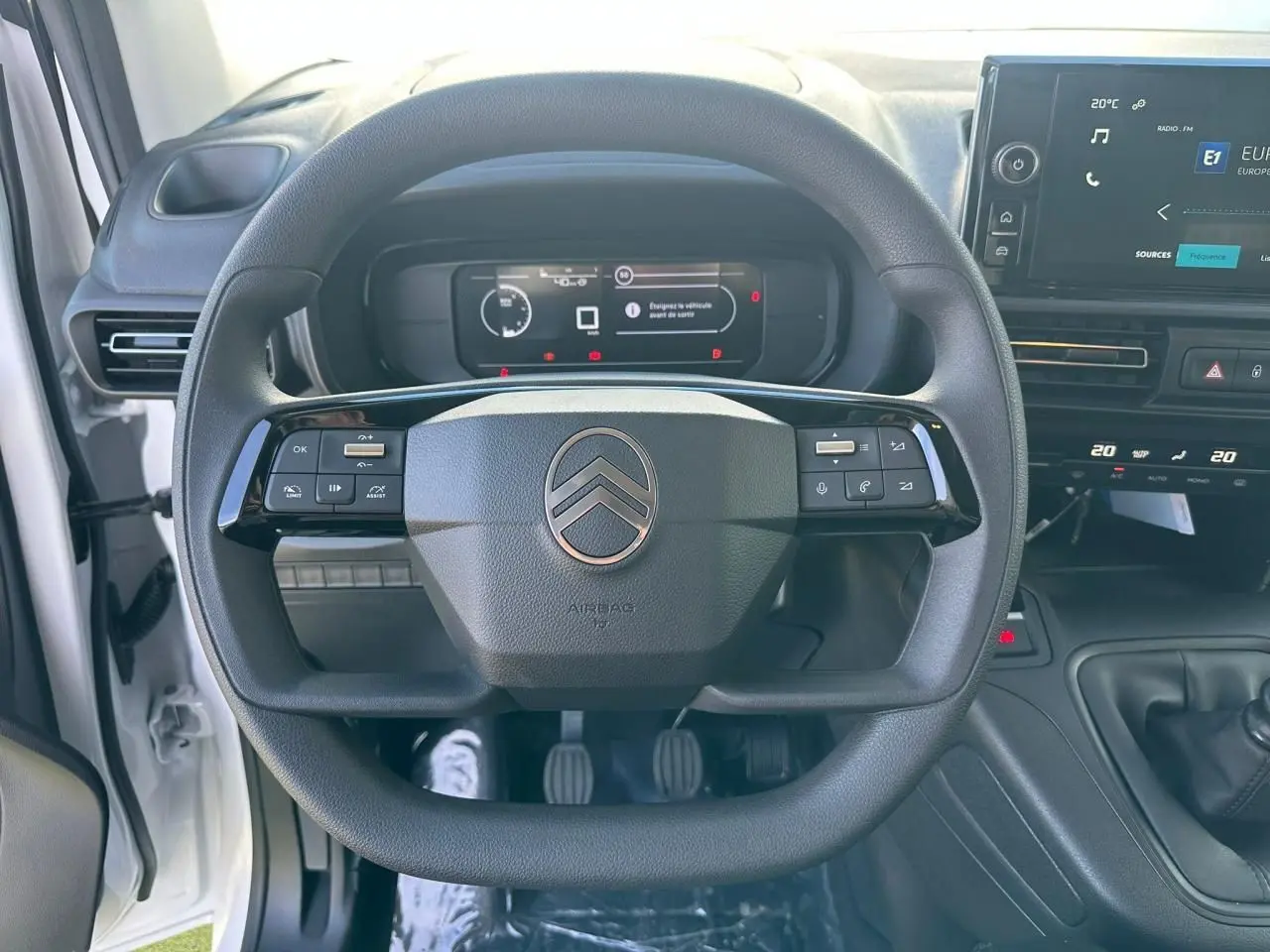 Vue rapprochée du volant multifonctions noir du Citroën Berlingo blanc Icy avec tableau de bord numérique et écran tactile.