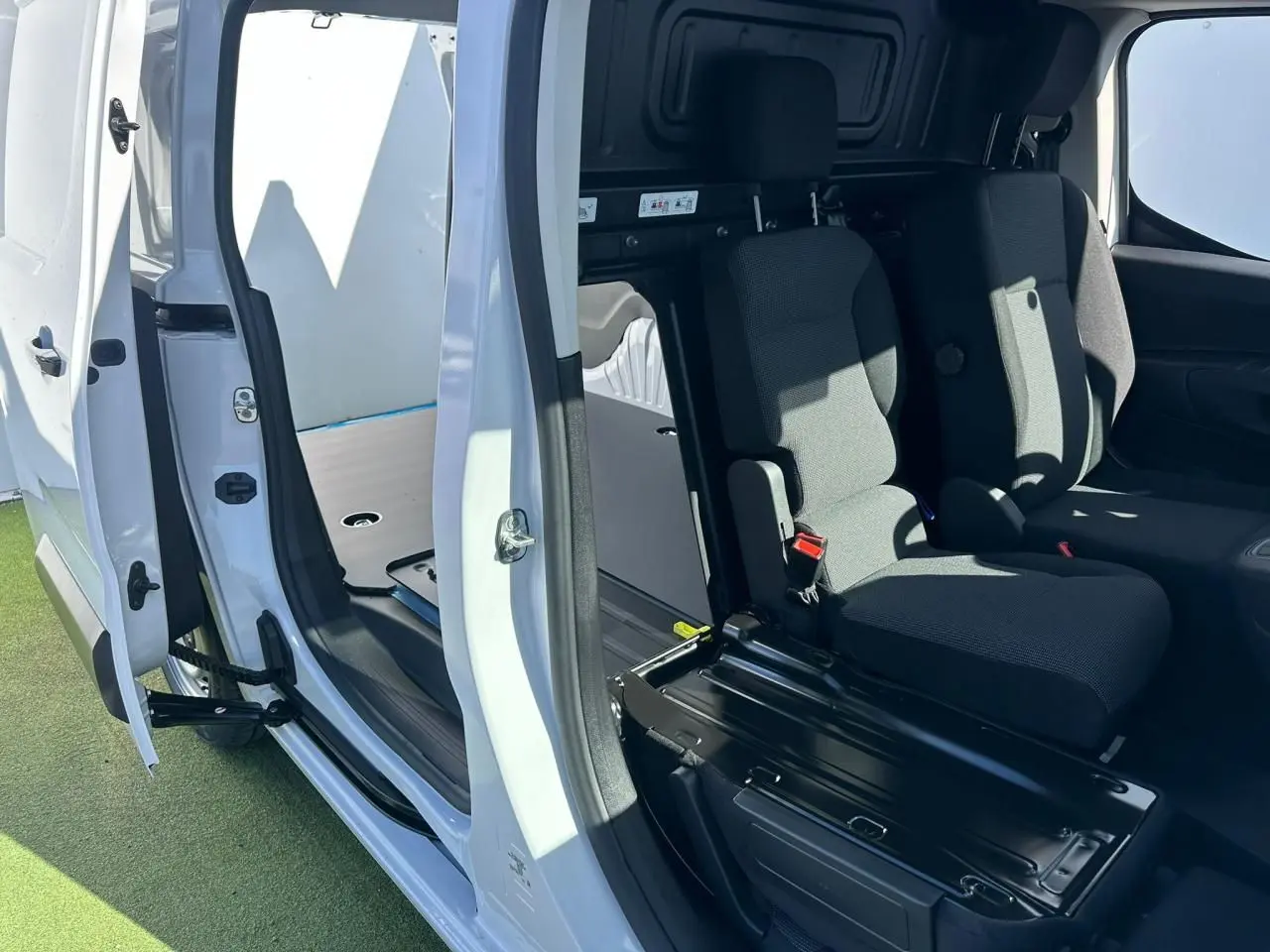 Vue intérieure côté droit du Citroën Berlingo blanc Icy avec porte latérale ouverte et banquette passager 2 places visible.