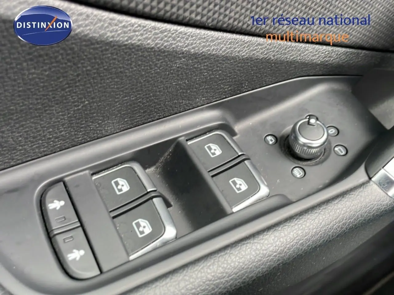 Gros plan sur les commandes des vitres et rétroviseurs côté conducteur d’un Audi Q2 noir mito metal.