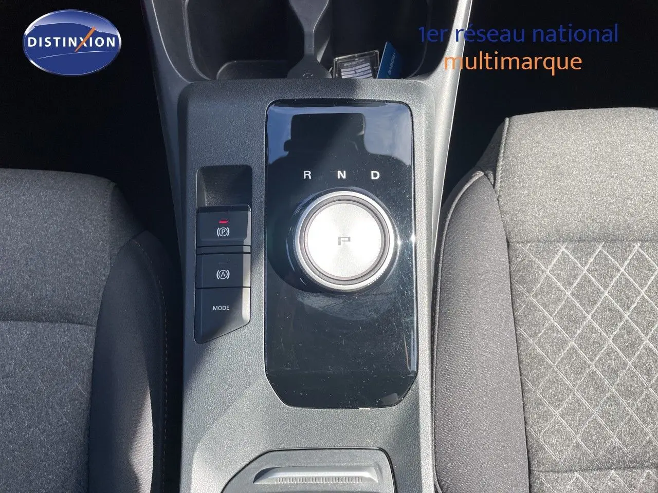 Vue plongeante sur la console centrale noire brillante du MG3 2024, avec molette de boîte auto et sièges tissu gris.