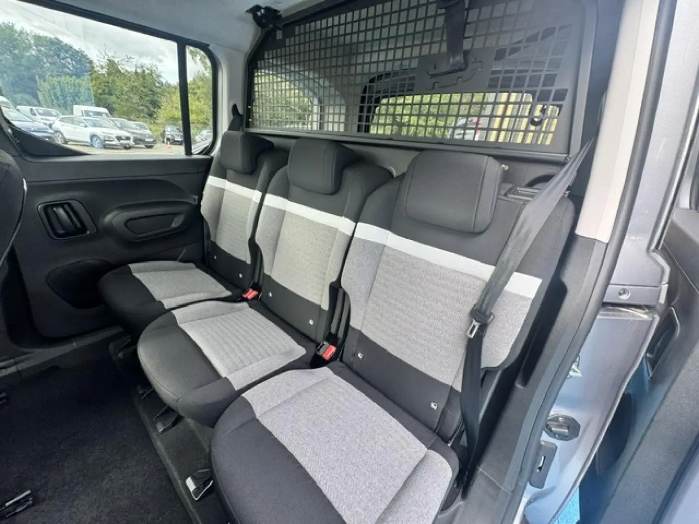 Vue intérieure côté droit des trois sièges individuels arrière gris clair et foncé du Citroën Berlingo Gris Acier 2026, avec séparation grillagée.