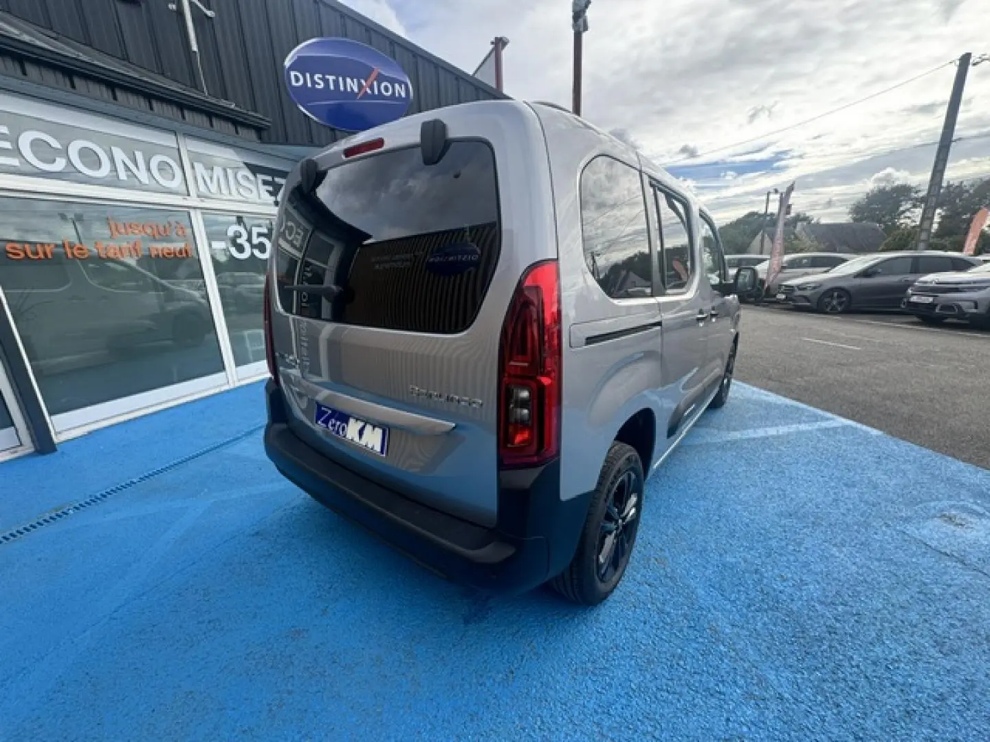 Vue 3/4 arrière droite du Citroën Berlingo gris acier avec vitres arrière teintées et jantes alu noires.