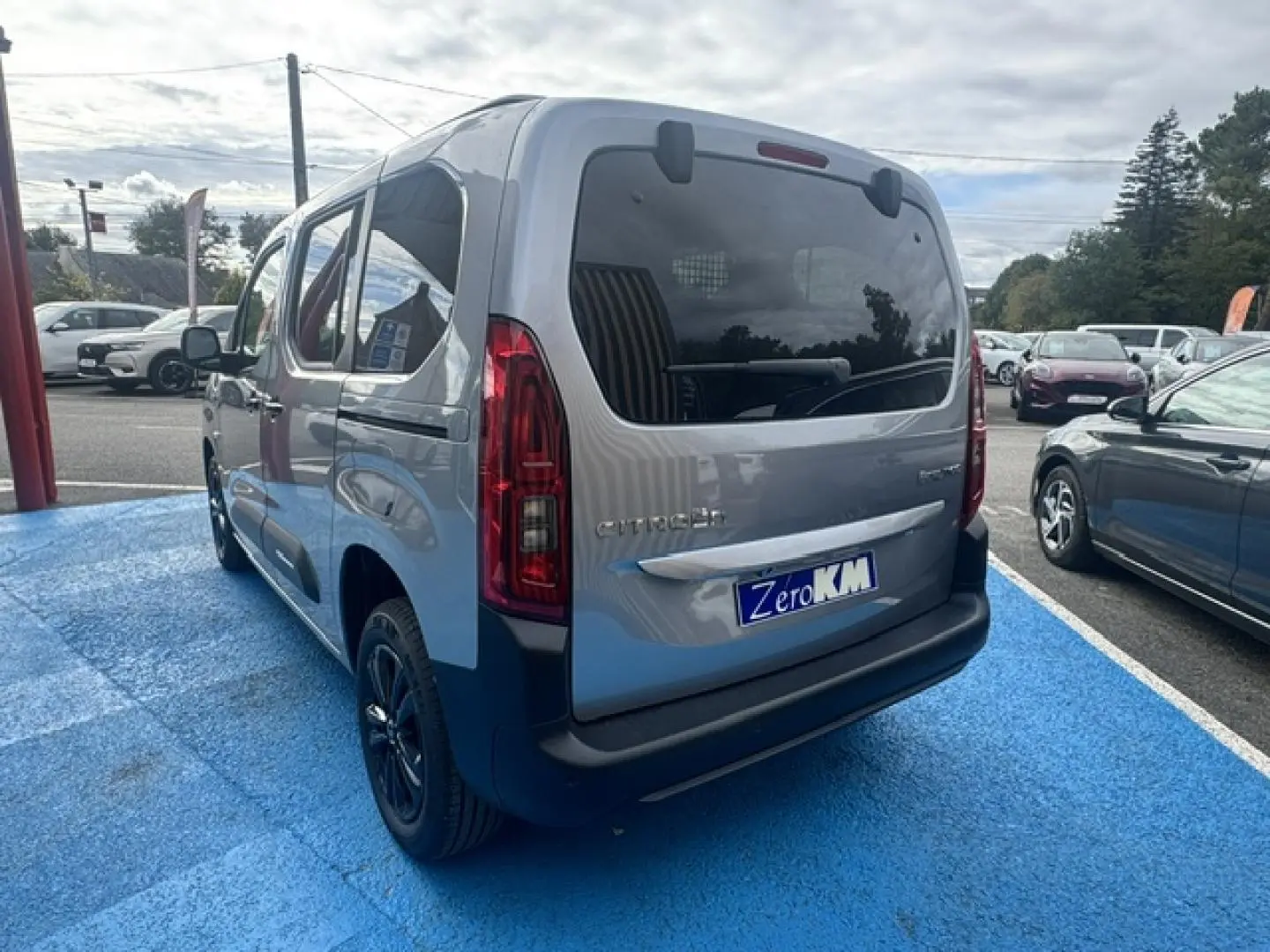 Vue 3/4 arrière droite du Citroën Berlingo gris acier avec vitres arrière teintées et jantes alu noires.