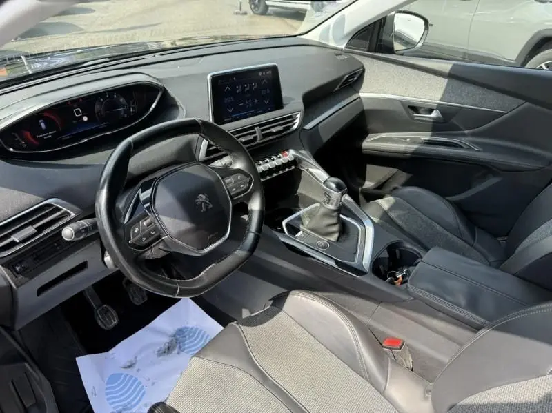 Intérieur du Peugeot 3008 2018 noir, vue côté conducteur, volant compact, écran tactile et levier de vitesse manuel visibles.