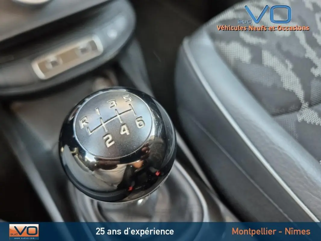 Gros plan sur le levier de vitesses manuel noir du FIAT 500X gris clair, intérieur avec sièges tissu et cuir.