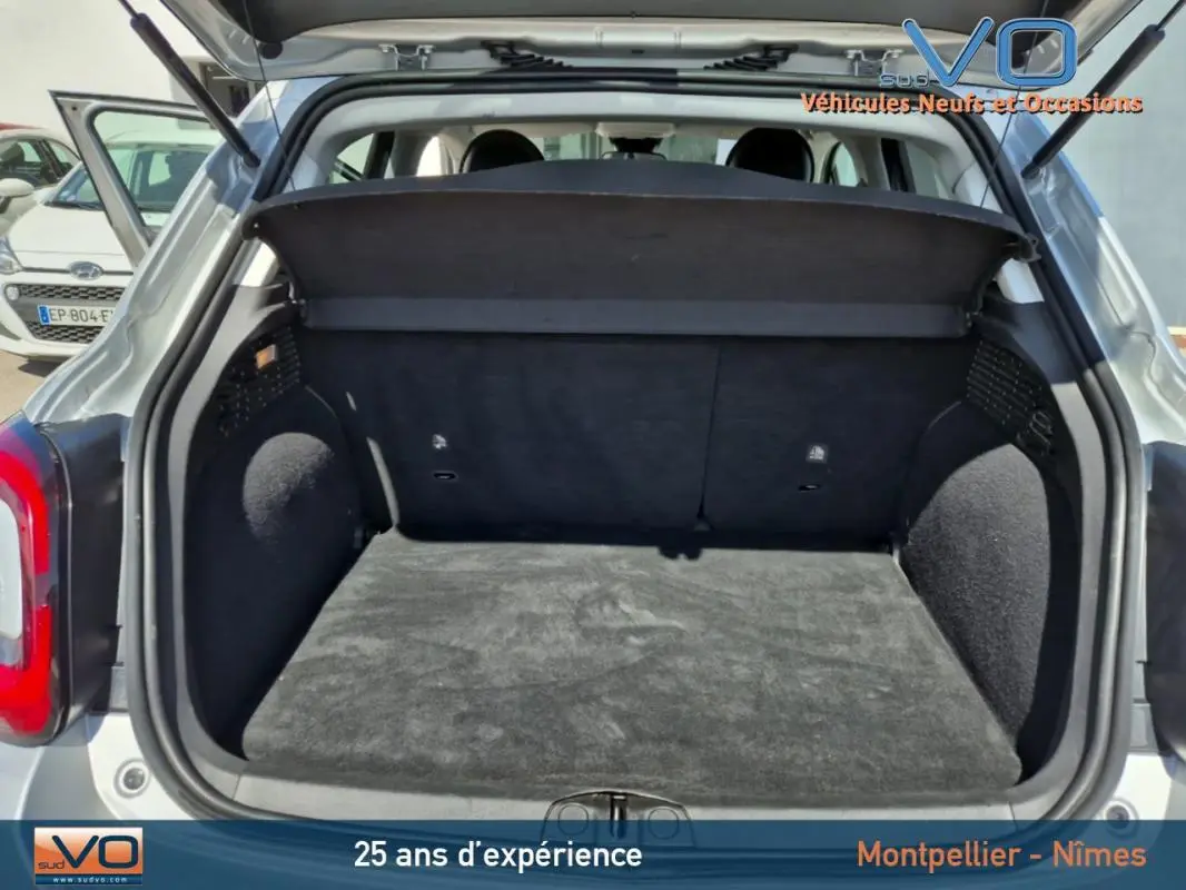 Coffre ouvert vu de l'arrière d'un FIAT 500X gris clair MY21, montrant l'espace de chargement vide et la plage arrière.