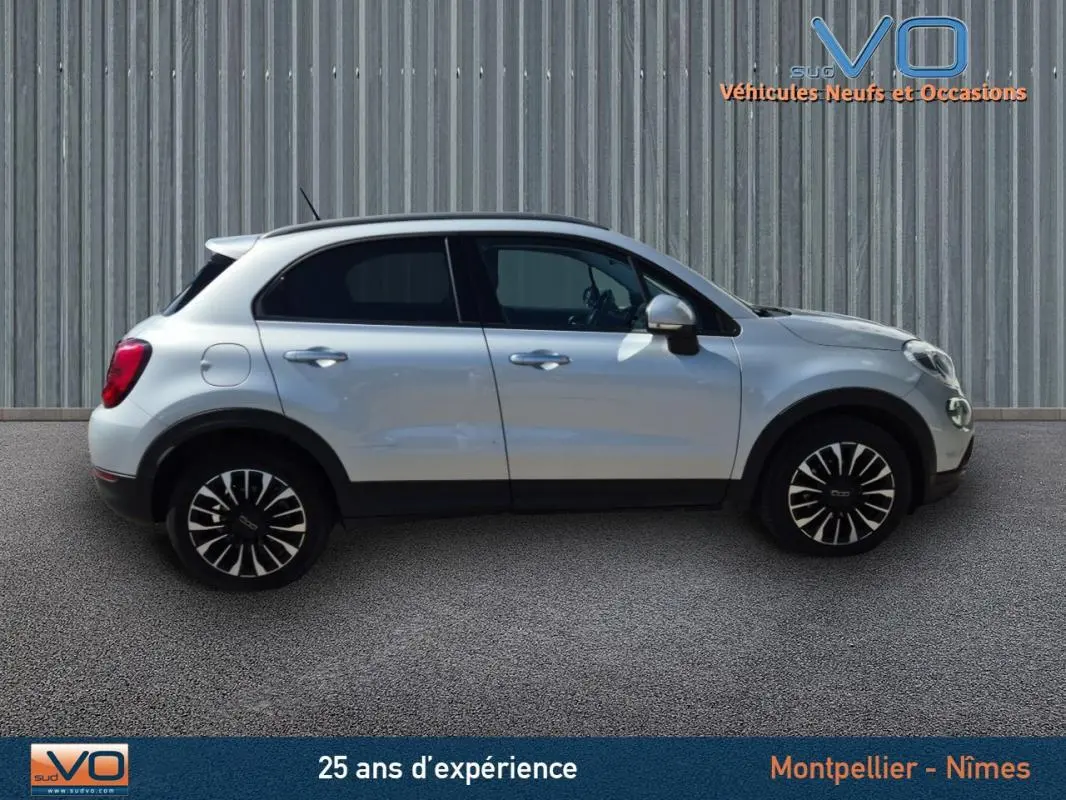 Profil côté gauche d'un FIAT 500X gris clair avec jantes alliage 17 pouces sur fond urbain neutre.