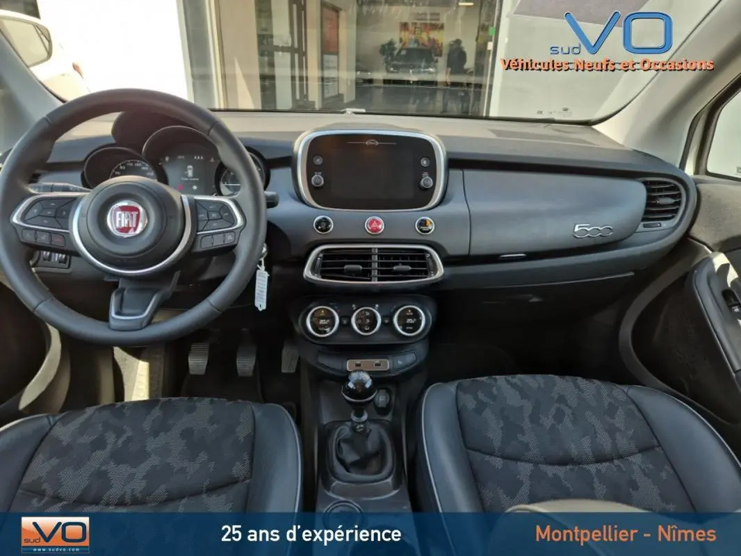 Intérieur de la Fiat 500X gris clair, vue frontale du tableau de bord avec volant multifonction et levier de vitesses manuel.