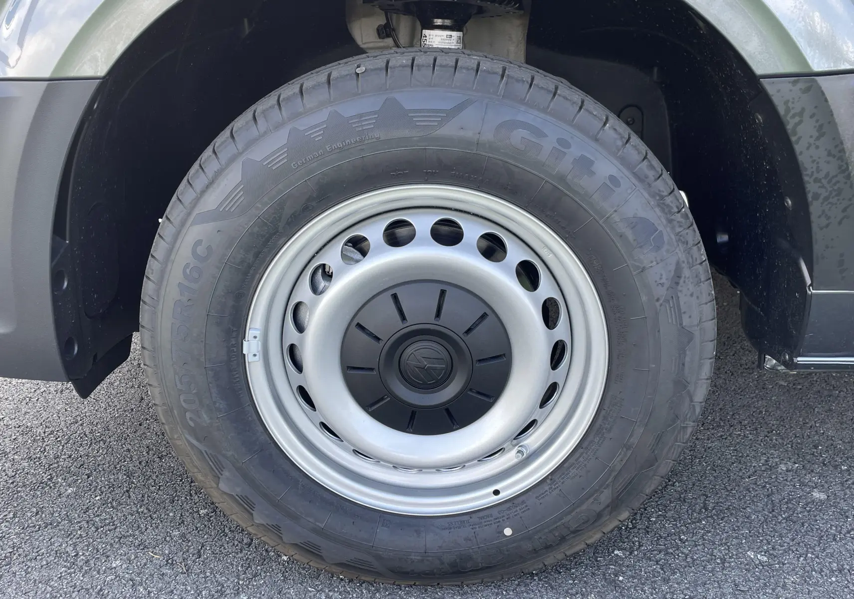 Gros plan sur la roue avant droite du Volkswagen Crafter Van gris Indium, jante acier avec logo VW central.