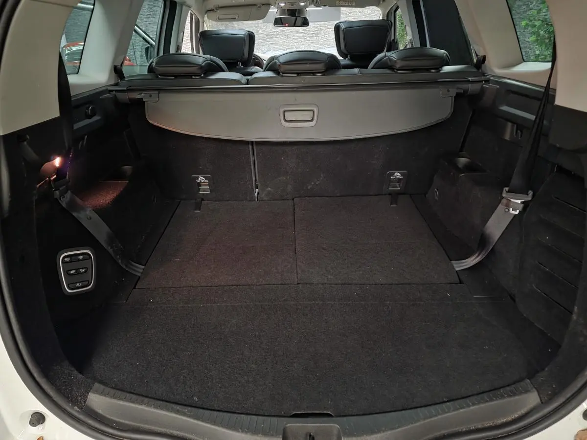 Coffre spacieux ouvert du Renault Scénic blanc 2017 avec banquette arrière et cache-bagages visibles.