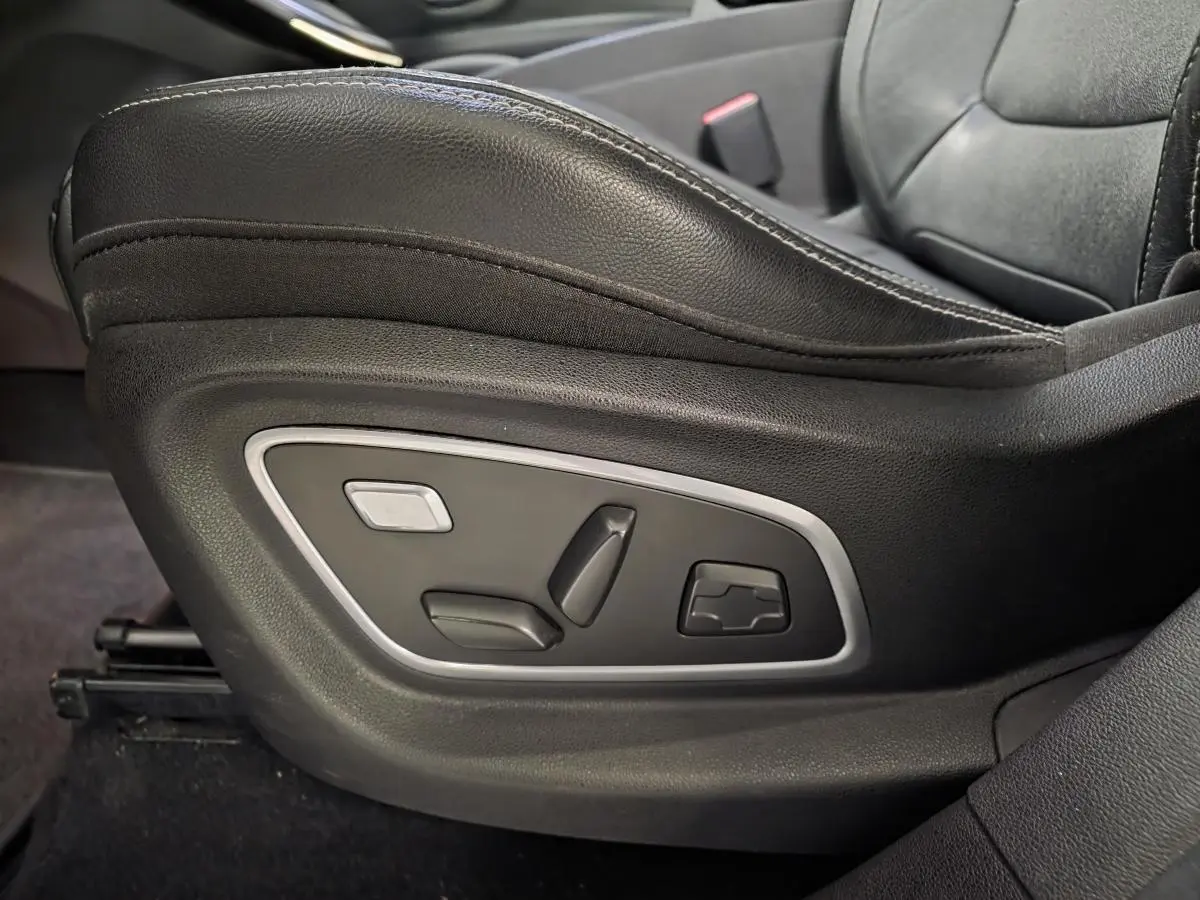 Gros plan sur les commandes électriques du siège conducteur en cuir carbone foncé du Renault Scenic blanc de 2017.
