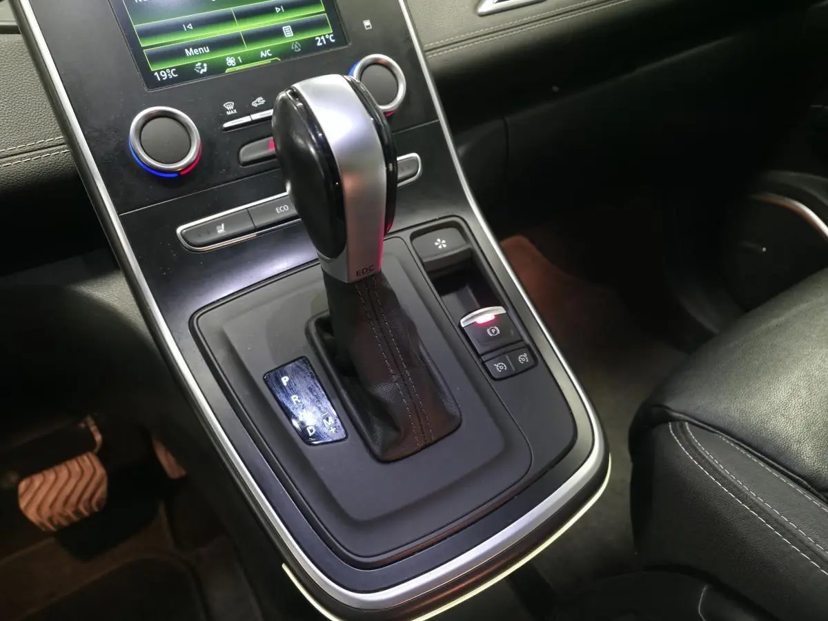 Gros plan sur la console centrale du Renault Scénic blanc 2017, mettant en valeur le levier de vitesse automatique EDC et les commandes adjacentes.