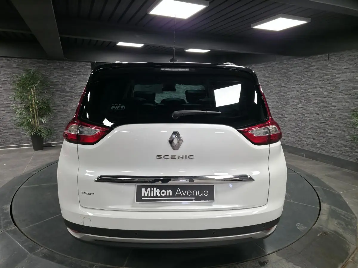 Vue arrière d'un Renault Scénic blanc nacré avec toit noir dans un showroom intérieur.