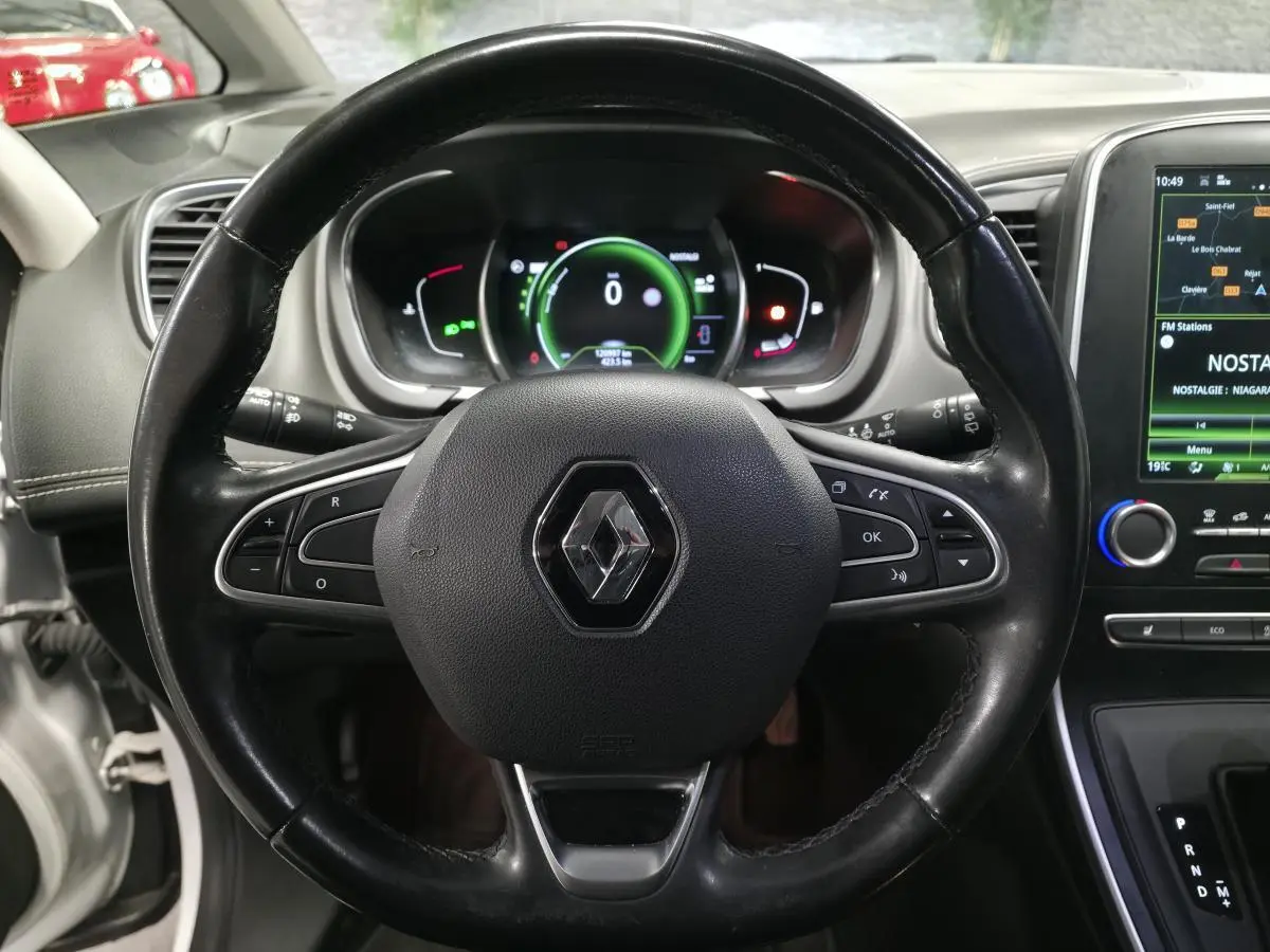 Volant cuir noir avec logo Renault, tableau de bord numérique et écran tactile central dans Renault Scenic blanc 2017.