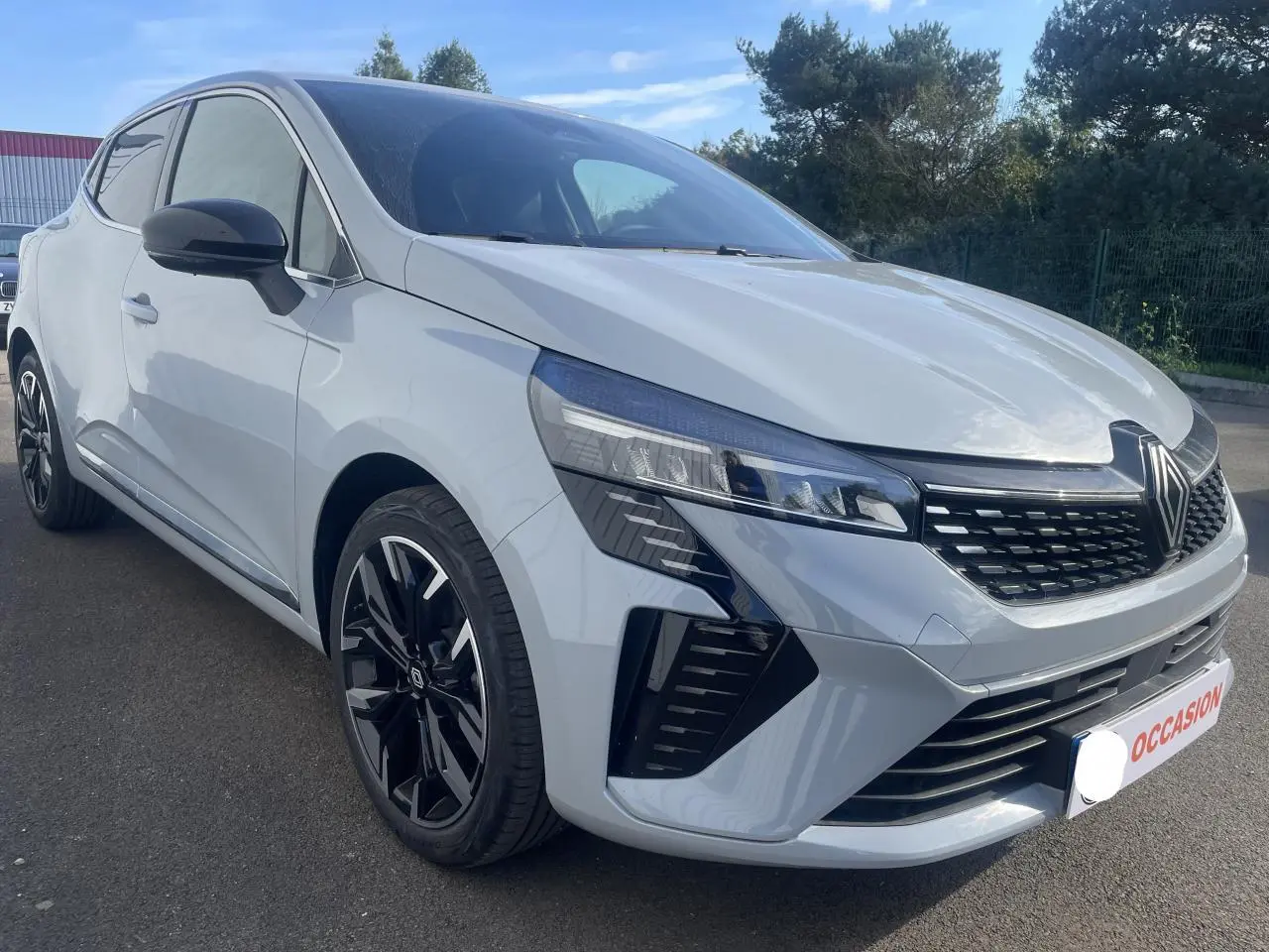 Renault Clio gris Rafale vue 3/4 avant droit avec jantes alliage noires et calandre marquée Renault.