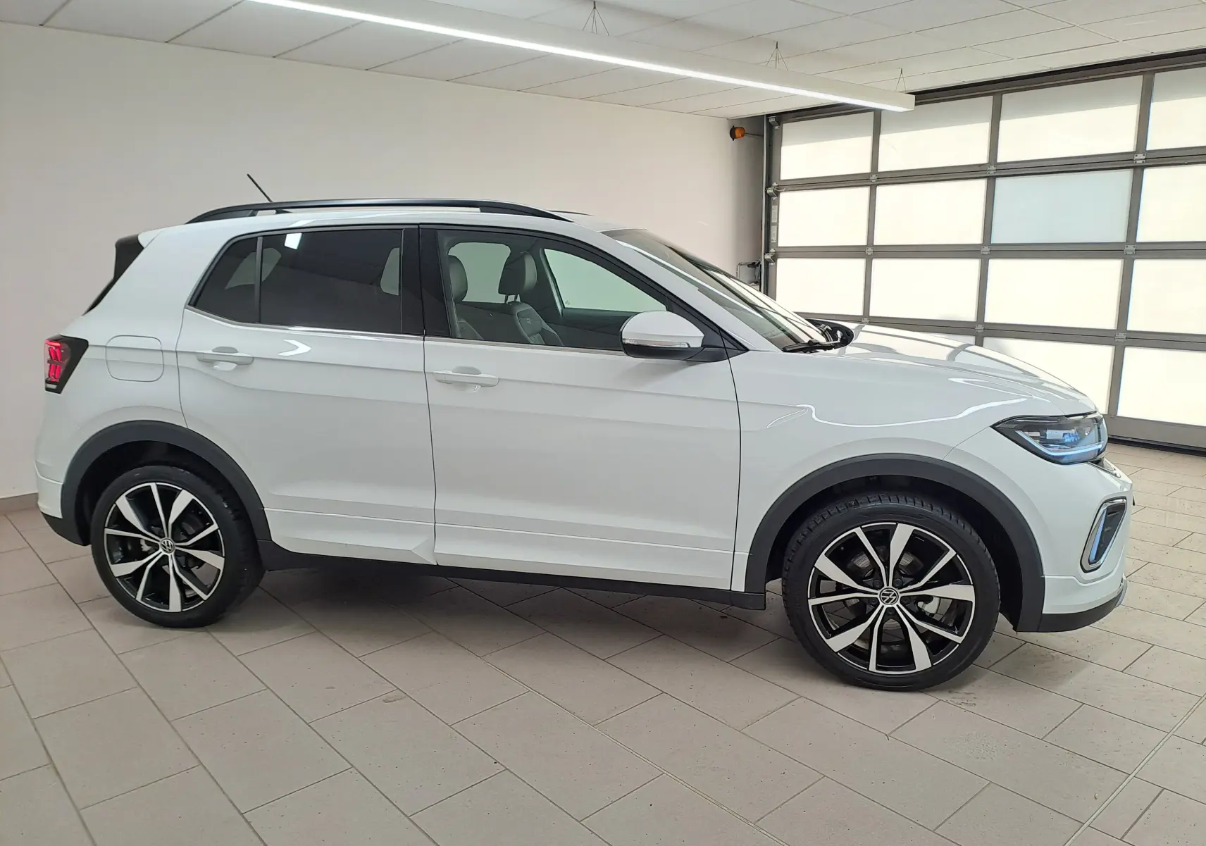 Volkswagen T-Cross 2025 blanc pur en vue 3/4 avant droit, avec phares LED et jantes alliage R-Line visibles.
