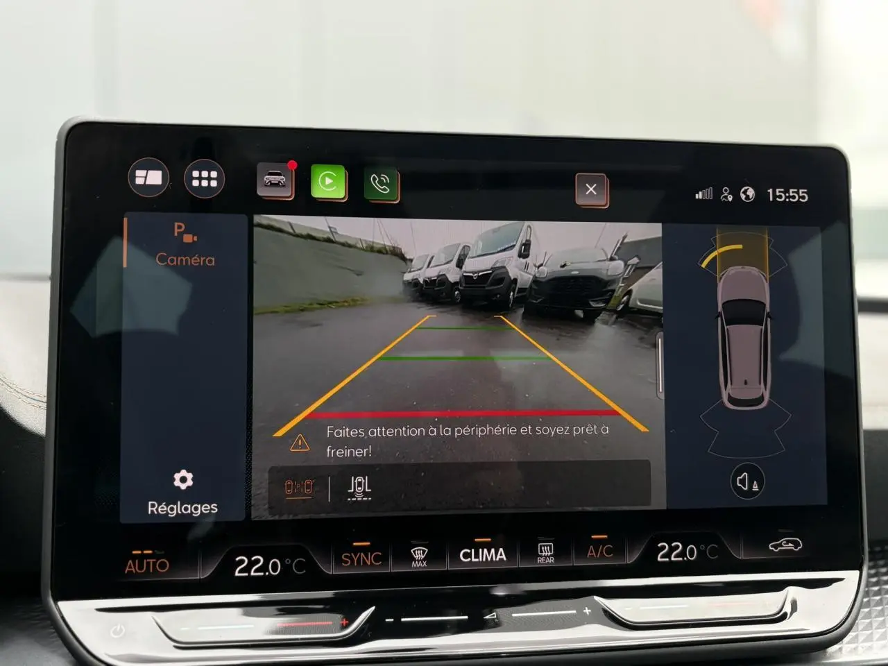 Écran tactile intérieur montrant la caméra de recul avec vue arrière sur un parking, tableau de bord moderne noir.