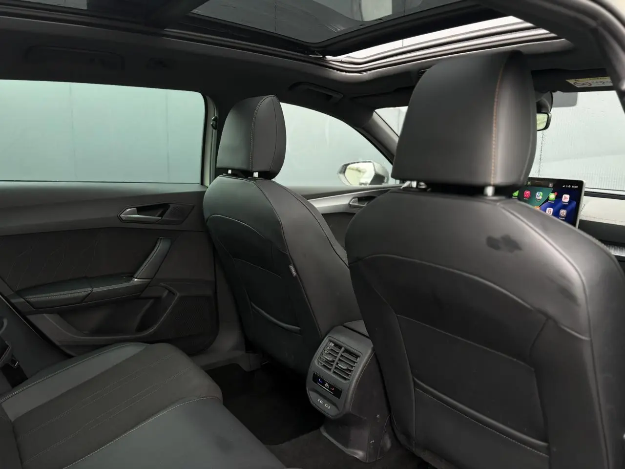 Vue arrière de l'habitacle noir cuir de la CUPRA LEON ST 1.5 e-TSI 150 DSG avec toit ouvrant panoramique et commandes climatisation.