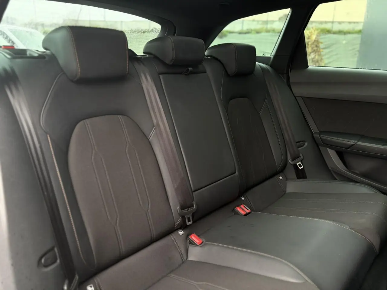 Vue intérieure des sièges arrière noirs du CUPRA LEON ST 2025, avec surpiqûres contrastantes et ceinture de sécurité visible.