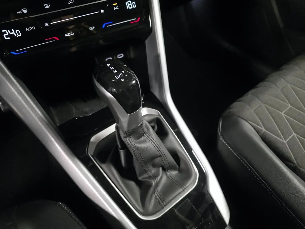Gros plan sur le levier de vitesse automatique noir et argenté du Volkswagen T-Roc 2025 avec sellerie tissu gris.