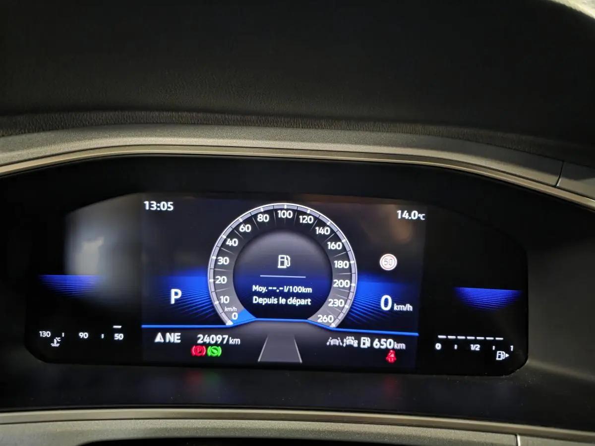 Tableau de bord digital du Volkswagen T-Roc 2025 affichant vitesse, température et autonomie, avec fond bleu.