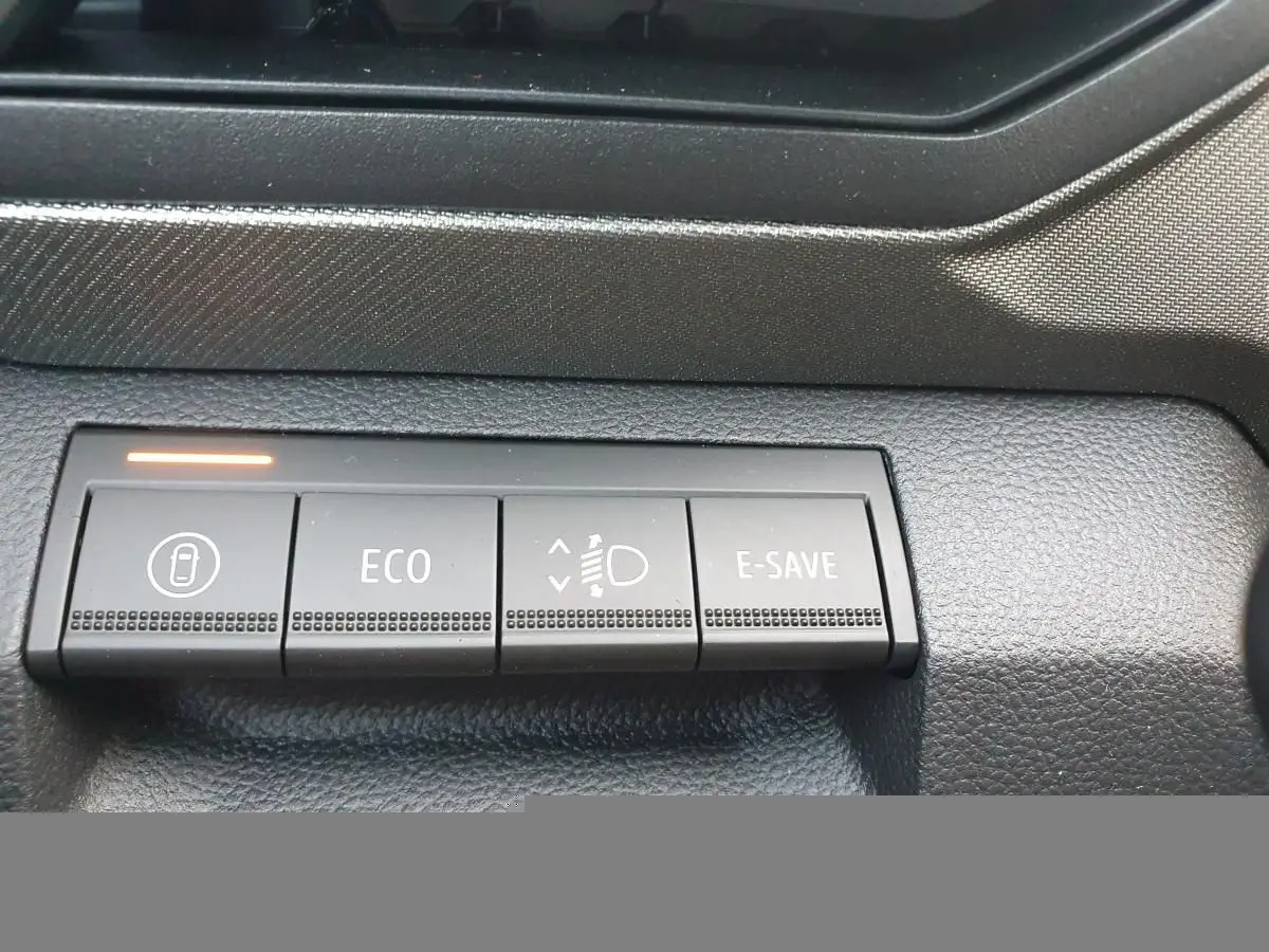 Gros plan sur les boutons de commande noirs du tableau de bord du Dacia Bigster, avec témoin lumineux orange allumé.