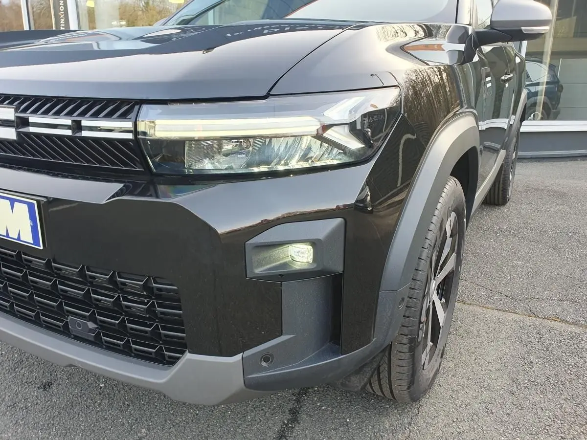 Vue 3/4 avant droit du Dacia Bigster noir Perla avec signature lumineuse LED et jante alliage 18 pouces diamantée.