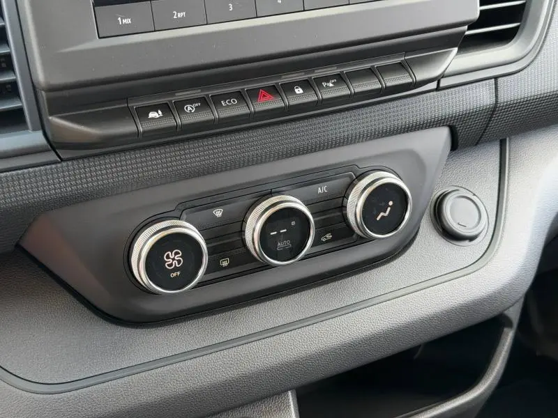 Gros plan sur la console centrale du Renault Trafic Fourgon 2024, montrant les commandes de climatisation et les boutons de fonction.