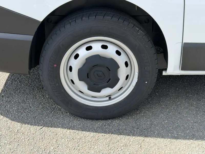 Gros plan sur la roue avant droite du Renault Trafic Fourgon blanc Glacier, avec jante acier et logo Renault central.