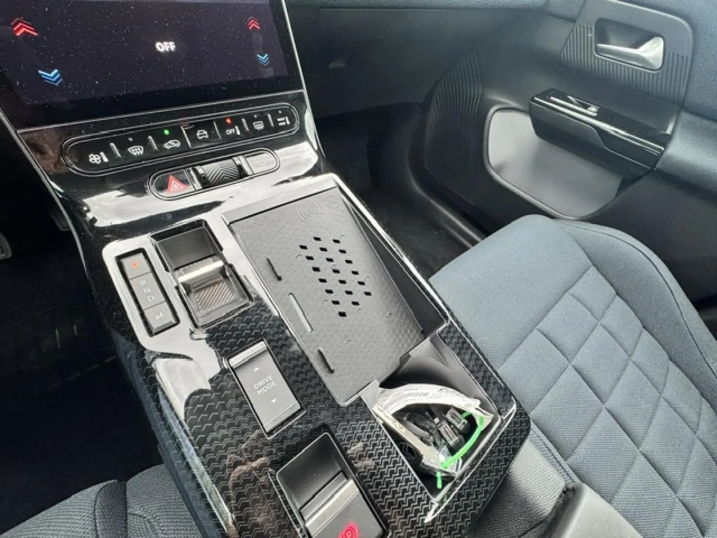 Vue intérieure centrée sur la console centrale noire brillante et siège tissu bleu du Citroën C5 Aircross 2026.