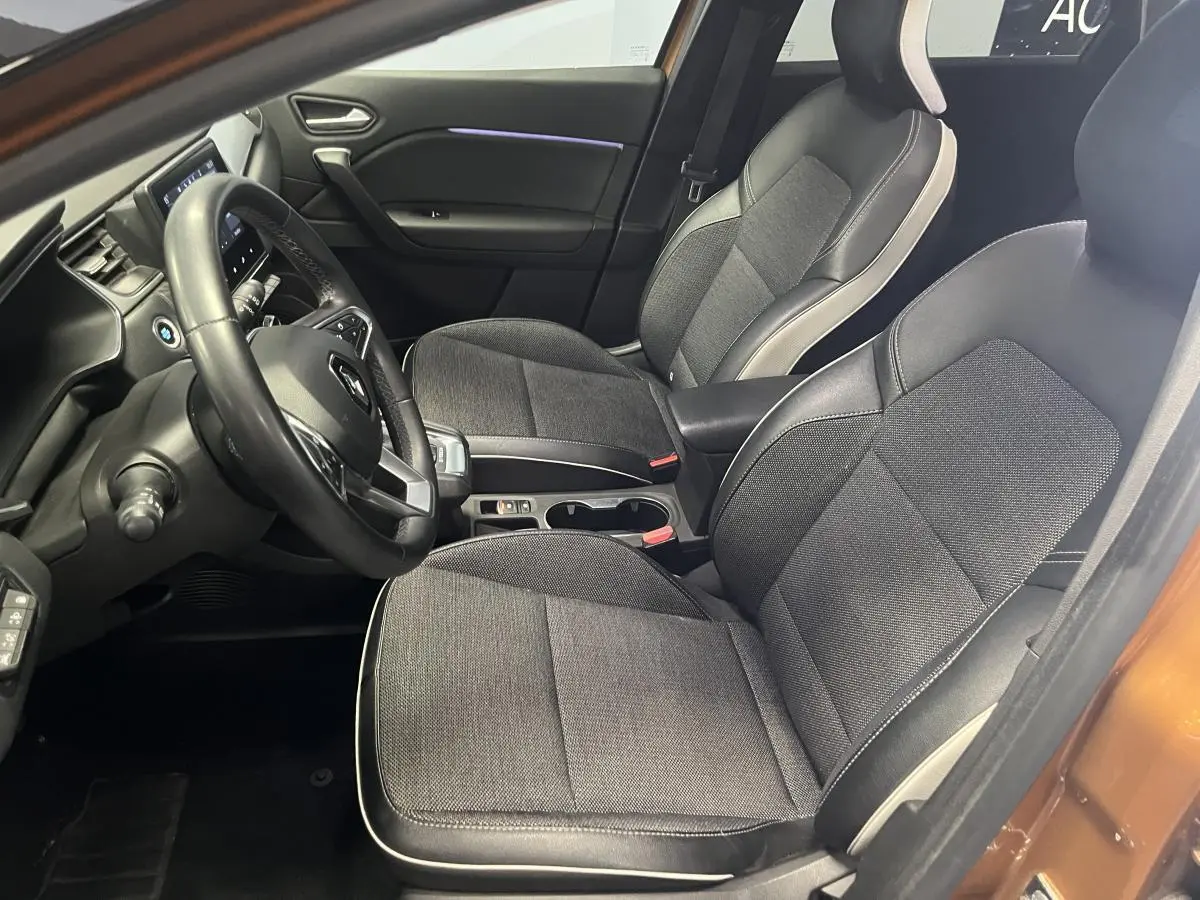Vue intérieure côté conducteur du Renault Captur orange 2022, sièges tissu et cuir gris avec console centrale noire.