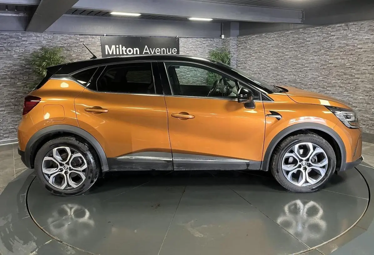 Profil droit d'un Renault Captur orange 2022 avec toit noir et jantes alliage 18 pouces Pasadena diamantées.
