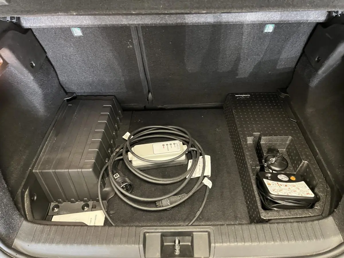 Coffre ouvert d'un Renault Captur hybride rechargeable 2022, montrant le rangement avec câble de recharge et kit de gonflage.